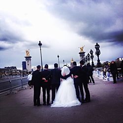 Silhouette of people on city street against cloudy sky