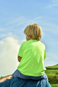 Rear view of boy sitting against sky