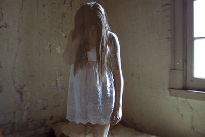 Rear view of woman standing against wall at home