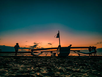 Silhouette man standing on beach against sky during sunset