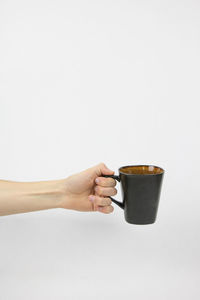 Hand holding coffee cup against white background