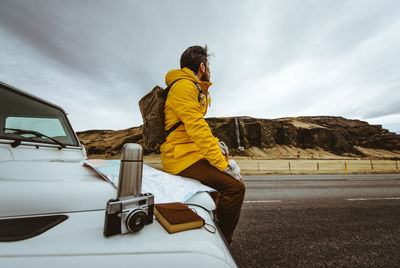 Side view of man skateboarding on road against sky