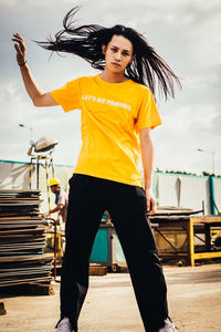 Beautiful young woman standing at construction site against sky