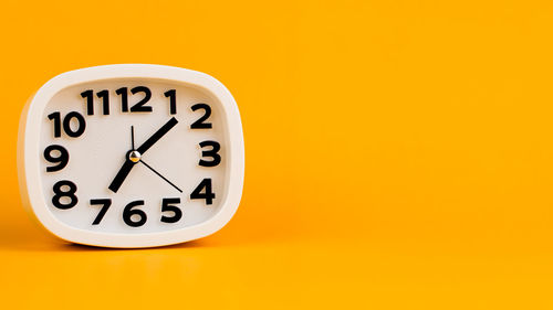 Close-up of clock against yellow background