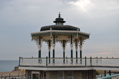 Low angle view of brighton palace pier against cloudy sky