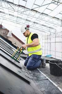 Side view of manual worker working with tools on metal at construction site