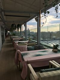 Empty chairs and tables in city against sky