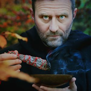 Portrait of man holding burning smudged sage and bowl