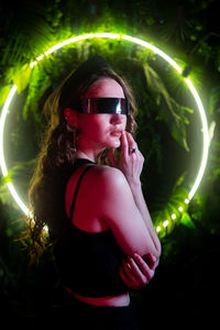Portrait of young woman wearing sunglasses while standing against sky at night