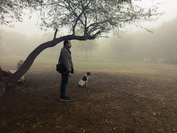 Full length of man with dog standing in rain