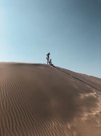 Couple on sand at desert against sky