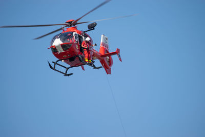 Low angle view of red airshow against clear blue sky