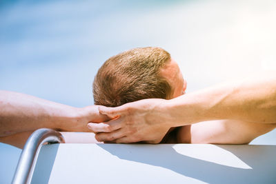 Close-up of man with hands behind head resting outdoors