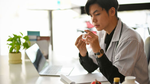 Young man using mobile phone while sitting on table