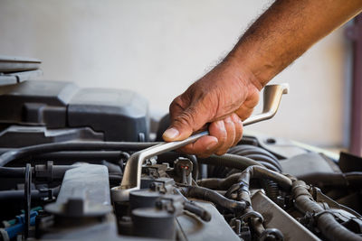 Cropped hand of mechanic repairing car in workshop