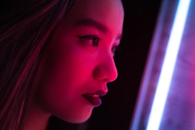 Close-up of young woman against black background