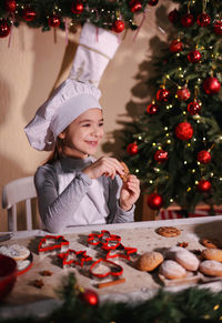 Portrait of young woman holding christmas tree at home