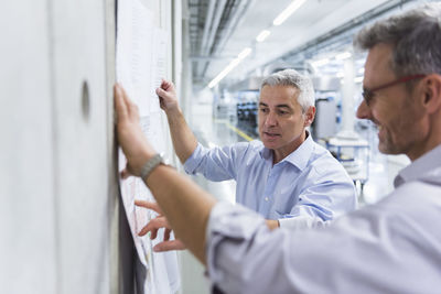 Two businessmen discussing construction plan at concrete wall