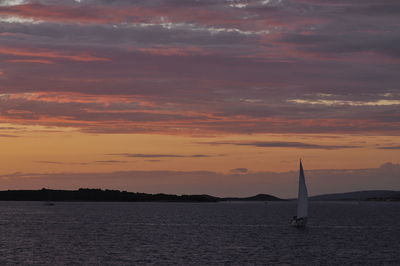 Sailboat sailing on sea against cloudy sky