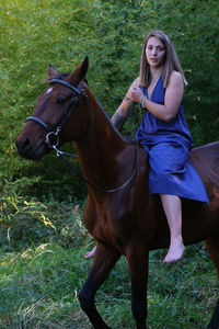 Portrait of young woman riding horse on field