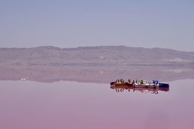 Swan shape pedal boats on lake against mountains