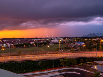 View of illuminated city against cloudy sky at night