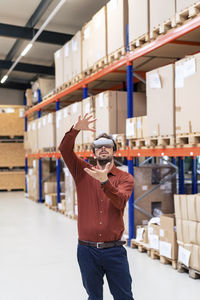 Businessman wearing virtual reality simulators gesturing in warehouse