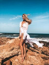 Full length of young woman on beach against sky