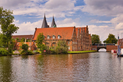 Bridge over river by buildings against sky