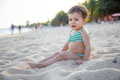 Portrait of cute baby sitting on sandy beach