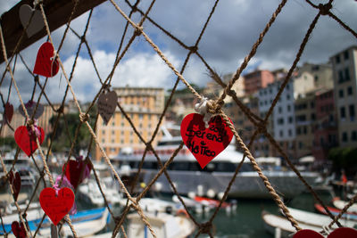 Close-up of heart shape decorations hanging on rope in city against sky