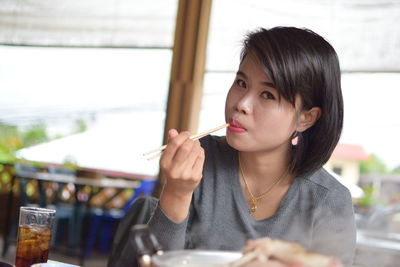 Portrait of woman eating food in restaurant