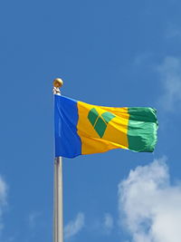 Low angle view of saint vincent and the grenadines flag against blue sky