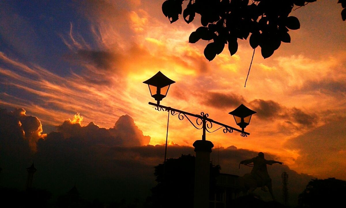 sunset, sky, silhouette, cloud - sky, orange color, low angle view, cloudy, tree, beauty in nature, nature, cloud, scenics, dramatic sky, tranquility, street light, idyllic, tranquil scene, outdoors, dusk, overcast