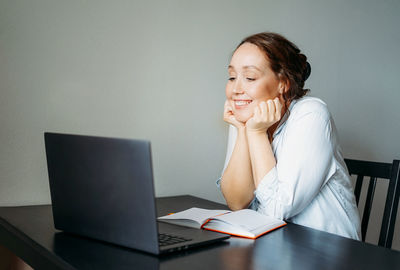 Young woman using mobile phone while sitting on table