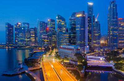 Illuminated modern buildings in city against sky at night