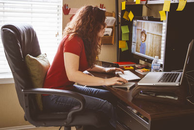 Woman using laptop while sitting on sofa at home