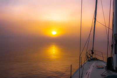 Sailboat sailing on sea against sky during sunset