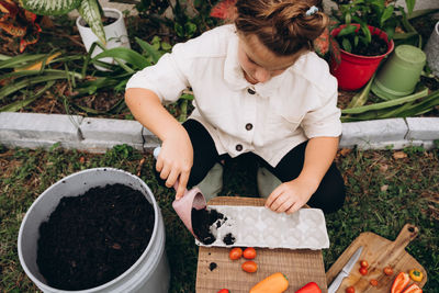 Girl planting seeds in the soil in carton container