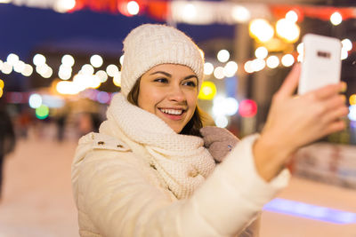 Portrait of smiling young woman standing in city during winter