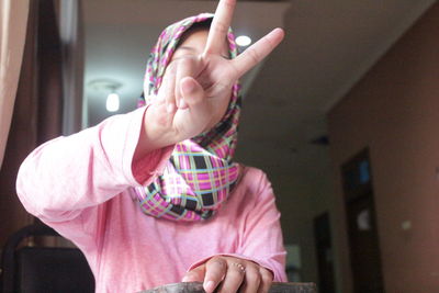 Young woman showing peace sign while sitting at restaurant