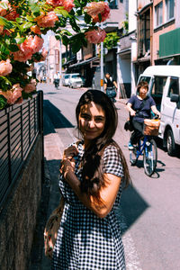 Portrait of young woman standing on street in city