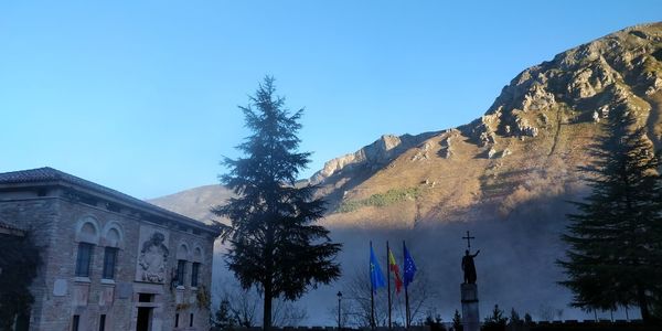 Low angle view of buildings and mountains against clear blue sky