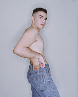 Portrait of shirtless man standing against white background