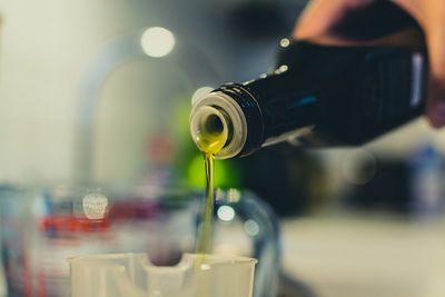 Cropped image of woman pouring olive oil in jar