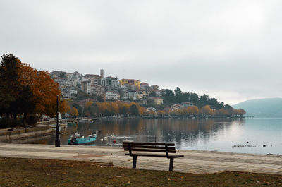 Bench by lake against sky