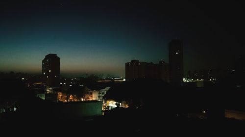 Illuminated buildings against clear sky at night