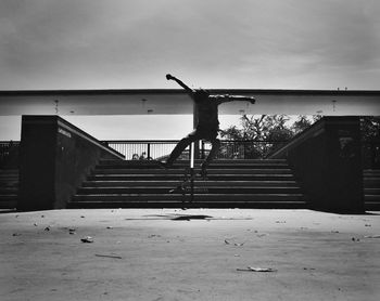 Man sitting on railing by beach against sky