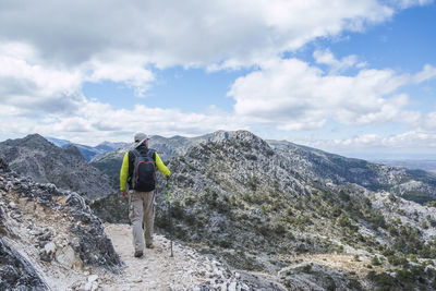 Rear view of man hiking on mountain against sky