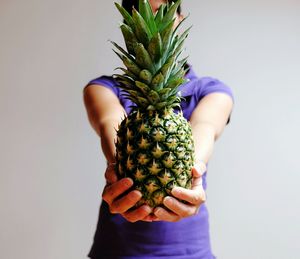 Close-up of hand holding fruit against white background